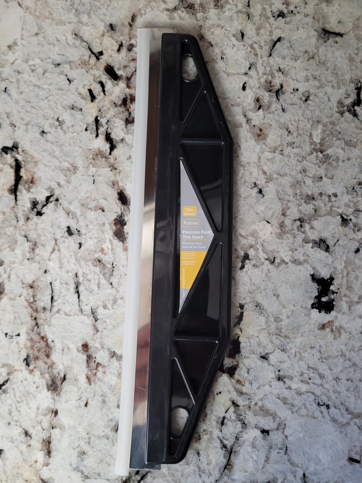 Paint trim guard placed along a wall edge for baseboard protection